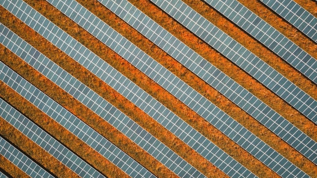 Vista aérea vertical de usina solar, com fileiras de painéis fotovoltaicos dispostos lado a lado (Foto Barney Elo/Pixabay)