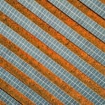 Vista aérea vertical de usina solar, com fileiras de painéis fotovoltaicos dispostos lado a lado (Foto Barney Elo/Pixabay)