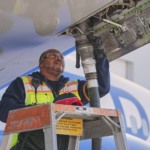 Técnico de manutenção de aviação, com colete de segurança amarelo fosforescente, faz o abastecimento com mangueira conectada verticalmente na parte de baixo da aeronave (Foto Thomas Vangel/Photography)